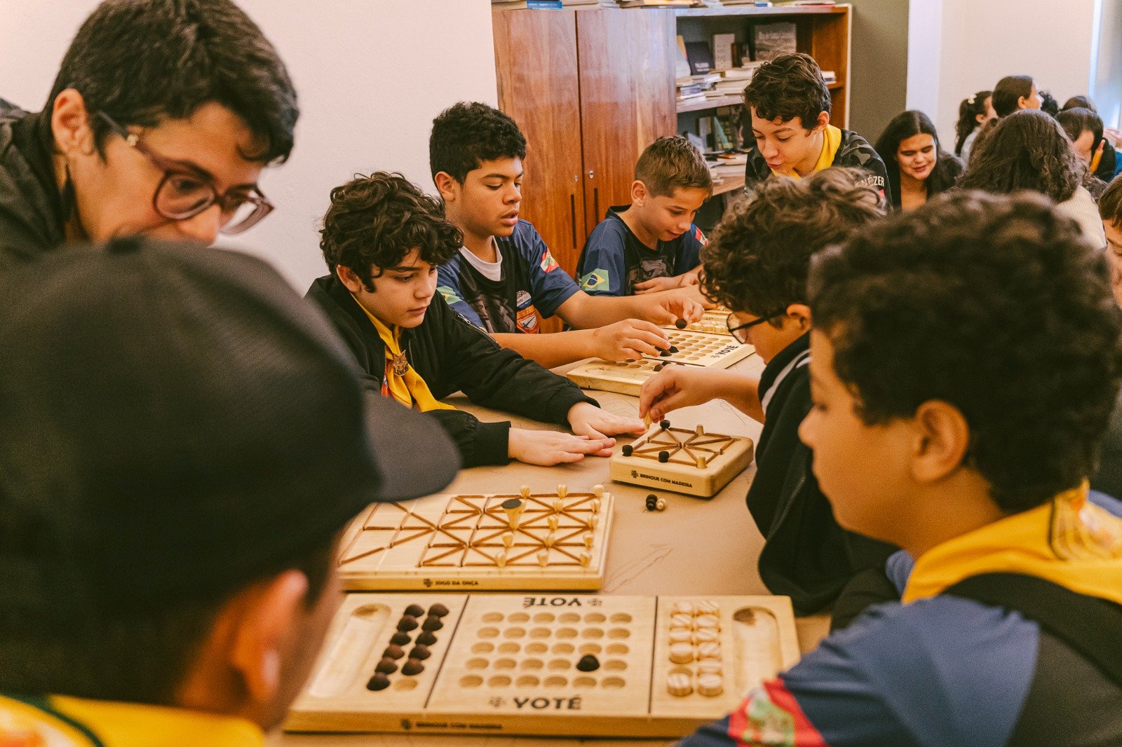 Crianças e mediadora interagem com os tabuleiros de madeira coloridos durante a oficina do Encontros Brincantes